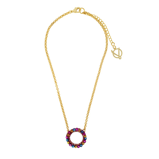 A gold-colored necklace with a round fuchsia, blue, and yellow hand-crocheted pendant and an 18 karat gold filled chain.