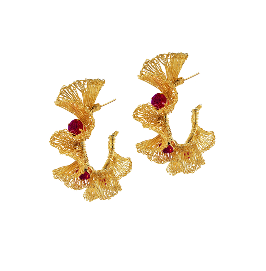 Gold earrings with red gemstones on a white background