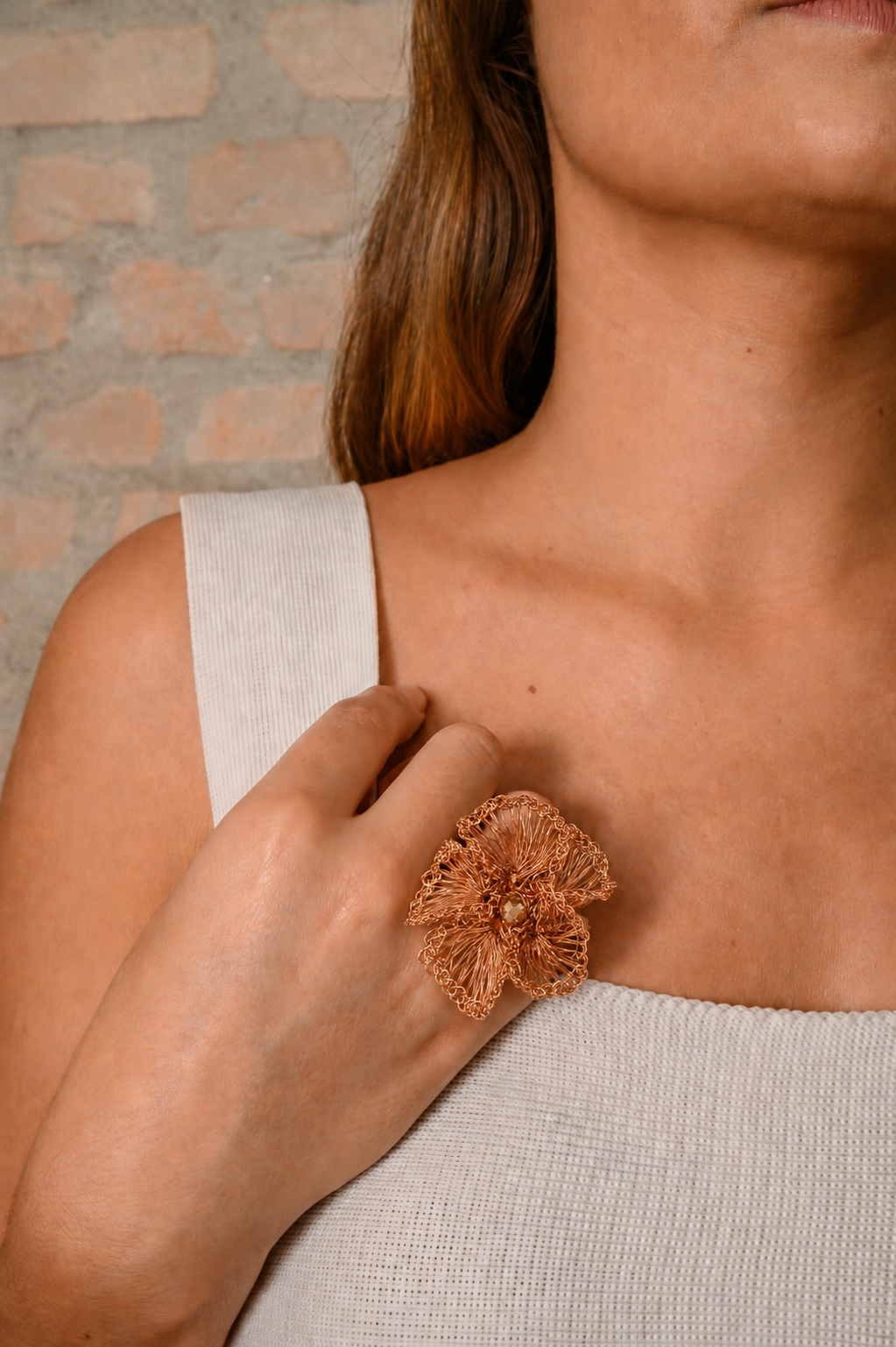 Person wearing a textured bronze ring brooch on a neutral background