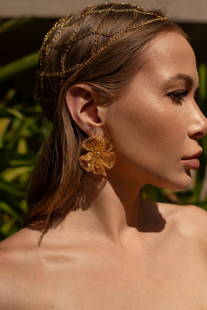 Woman wearing a gold headband and earrings with a blurred green  background - Handmade in Brazil, these floral hand crocheted earrings feature 18 karat gold filled wire, lightweight comfort, and hypoallergenic nickel free materials. 
