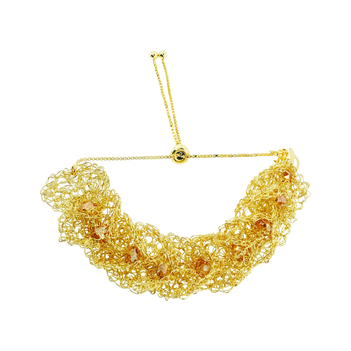 A gold-toned statement collar necklace featuring a dense, textured mesh of twisted chain links with small faceted amber-orange crystal accents, suspended from a delicate adjustable chain with a central gold bead. Shop the Ambar & Gold Calla Embrace Bracelet. Handmade in Brazil with golden crochet ruffles, amber crystals, and an adjustable sliding closure.