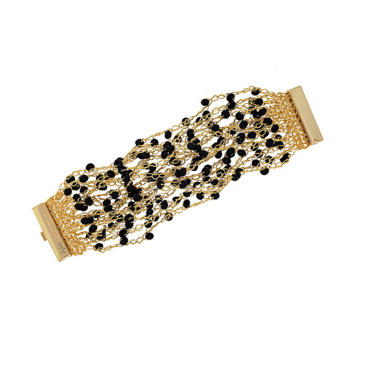 A hand-crocheted gold and black multi-string cuff bracelet with a shiny finish and sparkling crystals, secured by a magnetic clasp. Hand-crocheted gold cuff bracelet handmade in Brazil with 18 karat gold filled wire, black bead accents, sparkling crystals, and magnetic clasp.