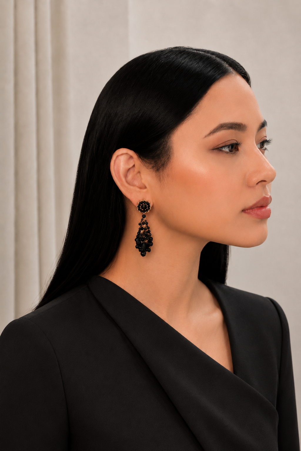 Woman wearing black earrings with a neutral background