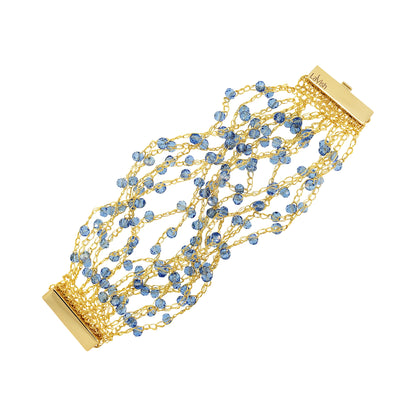 Gold bracelet with blue beads on a white background. Hand-crocheted gold cuff bracelet handmade in Brazil with 18 karat gold filled wire, sparkling blue crystal accents, and magnetic clasp.