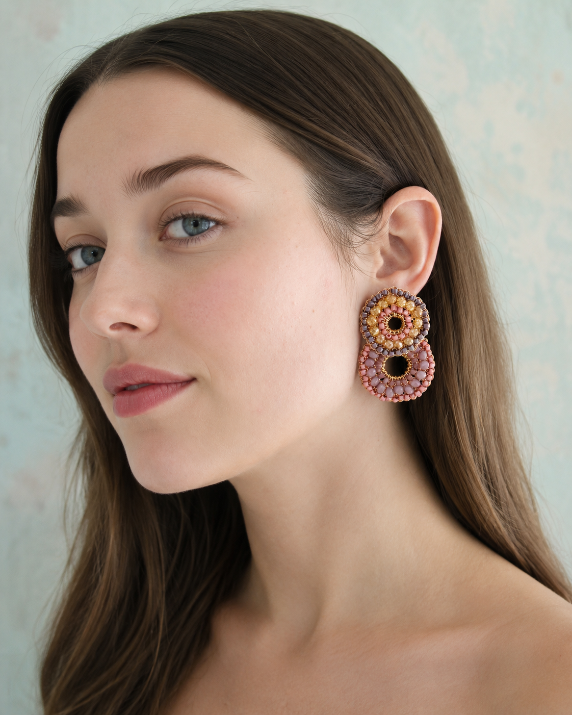 Woman wearing colorful beaded earrings against a neutral background
