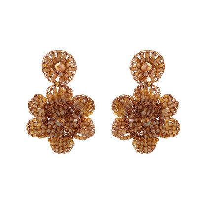 Pair of gold floral earrings on a white background. Mini floral hand-crocheted earrings handmade in Brazil with bronze enameled wire and amber bead accents.