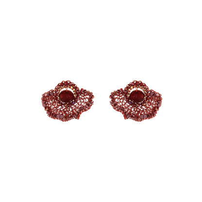 A pair of textured, scalloped red earrings with a central oval red stone, set against a plain white background. Shop Burgundy Mix Celosia Post Earrings, featuring a hand-crocheted fan design with shimmering crystals and beads. Lightweight and handmade in Brazil.