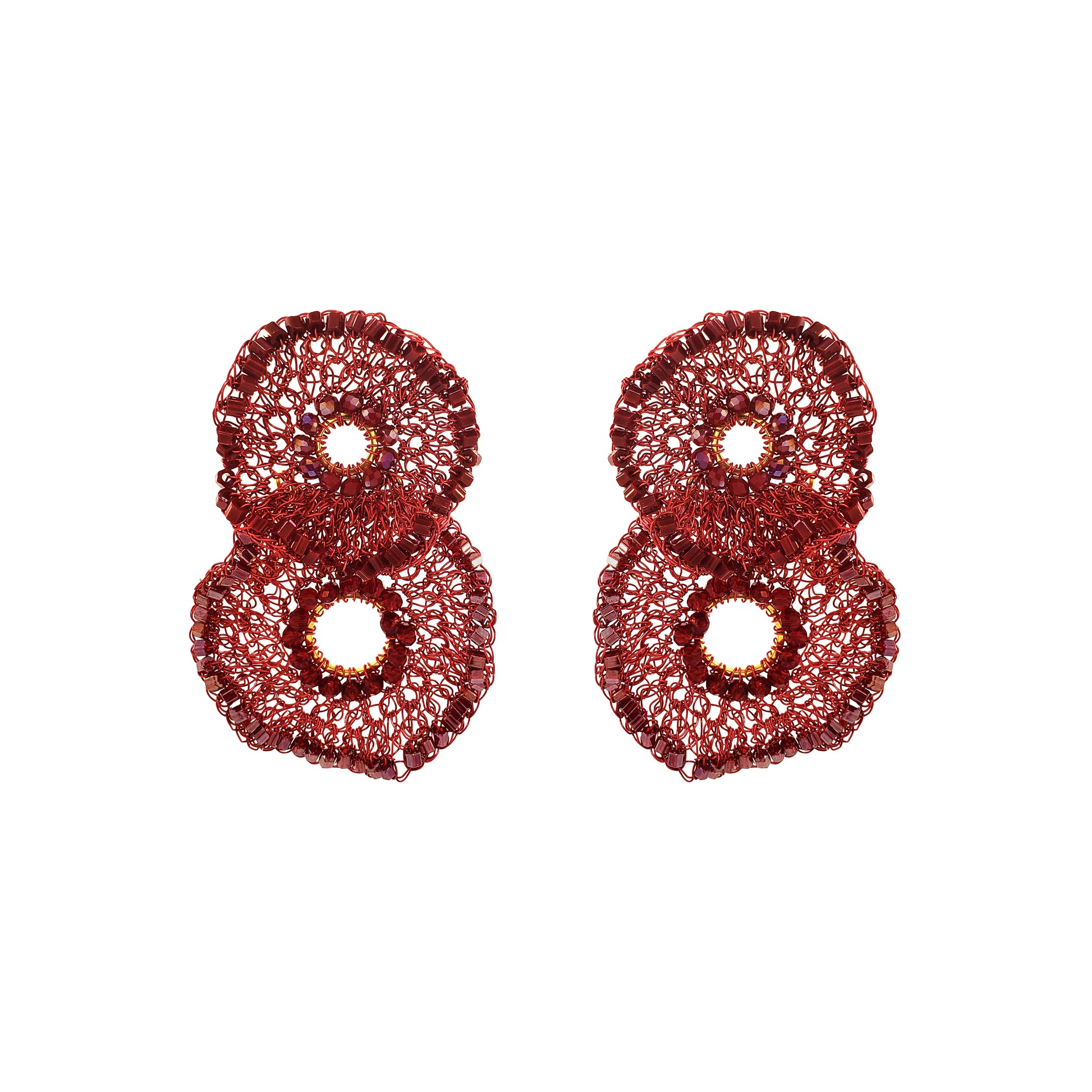A pair of textured, glittery red earrings shaped like stylized numbers 8, displayed on a clean white background. Shop the Crista Duo Earrings, hand-crocheted in Brazil with rich burgundy tones, shimmering bead accents and a lightweight double-circle design.