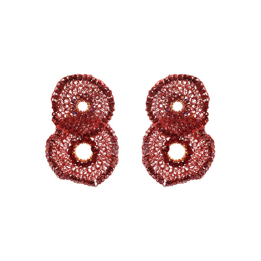 A pair of textured, glittery red earrings shaped like stylized numbers 8, displayed on a clean white background. Shop the Crista Duo Earrings, hand-crocheted in Brazil with rich burgundy tones, shimmering bead accents and a lightweight double-circle design.