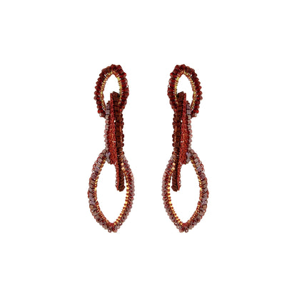 A pair of beaded drop earrings with a textured, looped design in deep red and brown tones, set against a plain white background. Shop the Burgundy Mix Demi Earrings, featuring three cascading hand-crocheted links with shimmering bead accents. Lightweight and handmade in Brazil.