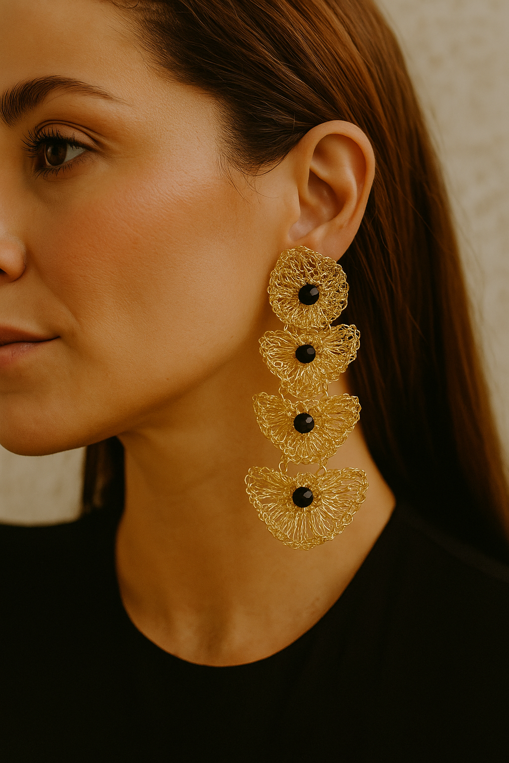 Close-up of a woman wearing gold earrings with black stones.