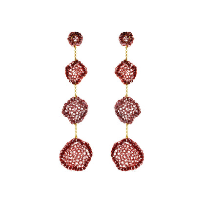 A pair of long drop earrings with three stacked textured circular segments in a deep red hue, separated by small gold chains, on a plain white background.