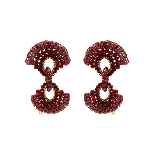 A pair of statement drop earrings crafted from faceted deep red gemstones and accented with gold-tone metal, shown against a plain white background. Red hand-crocheted Duo statement earrings with sparkling bead accents, fan-shaped details and a double-drop silhouette, handmade in Brazil.