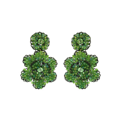 A pair of neon green mini blossom handcrafted crochet earrings with a black enameled wire base. Mini floral hand-crocheted dangle earrings handmade in Brazil with shiny enameled wire and sparkling forest green bead accents.