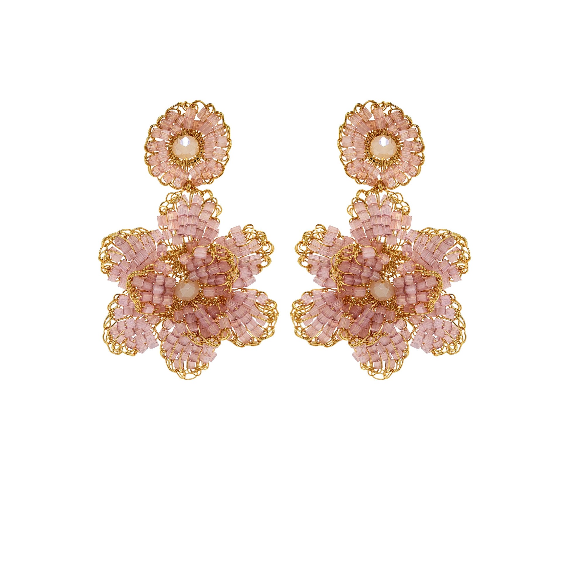 A pair of hand-crocheted earrings with gold and pink detailing, resembling a floral pattern, displayed against a plain background. Floral hand-crocheted dangle earrings handmade in Brazil with 18 karat gold filled wire and delicate mauve bead accents.