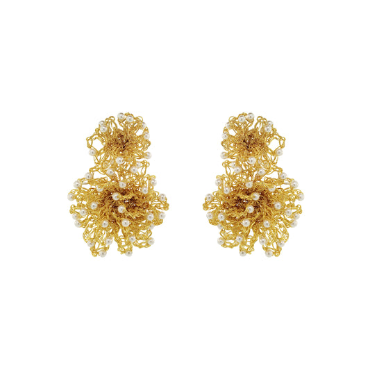 A pair of gold-toned statement earrings with intricate floral wirework and small white pearl accents, displayed on a solid white background. Hand-crocheted gold Double Mandala earrings with dimensional floral details and white pearl-like bead accents, handmade in Brazil.