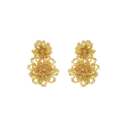 Pair of gold floral earrings on a white background. Hand-crocheted gold Double Mandala earrings with dimensional floral details and white pearl-like bead accents, handmade in Brazil.