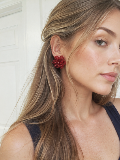 Close-up of a woman wearing a red floral earring with a white background