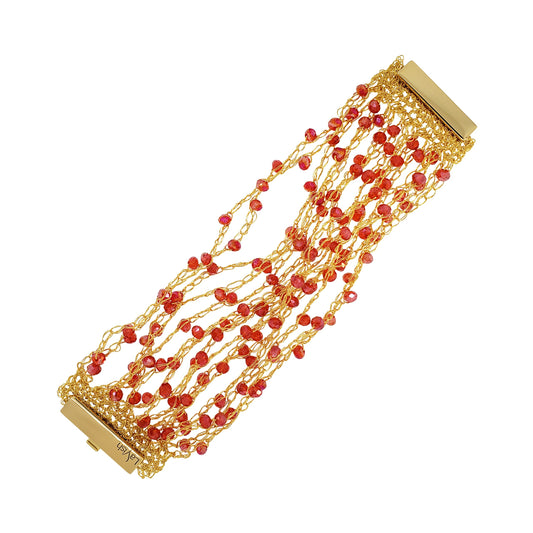 A hand-crocheted gold and red multi-string bracelet with a shiny metallic finish and sparkling crystals, secured by a magnetic clasp. Hand-crocheted gold cuff bracelet handmade in Brazil with 18 karat gold filled wire, sparkling red crystal accents, and magnetic clasp.