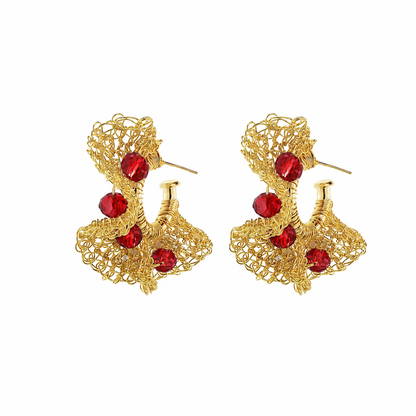 A pair of gold-toned filigree earrings with five faceted red crystal accents, displayed on a clean white background. Hand-crocheted in Brazil, these lightweight 18k gold-filled hoop earrings feature vibrant red crystals and Lavish’s signature artisan crochet technique.