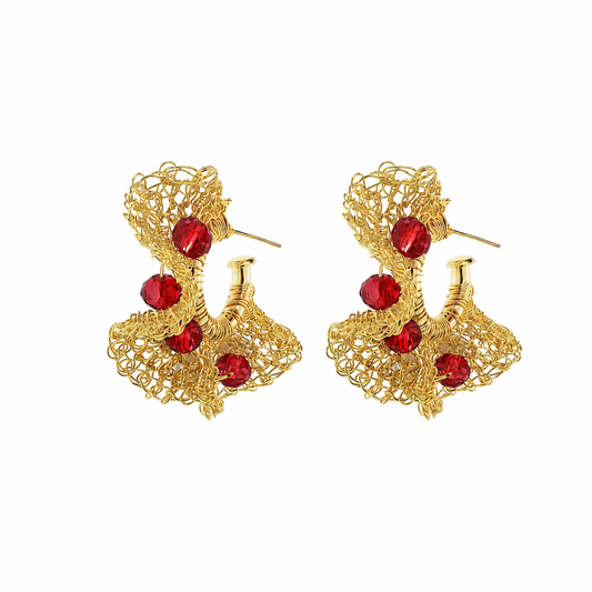 A pair of gold-toned filigree earrings with five faceted red crystal accents, displayed on a clean white background. Hand-crocheted in Brazil, these lightweight 18k gold-filled hoop earrings feature vibrant red crystals and Lavish’s signature artisan crochet technique.