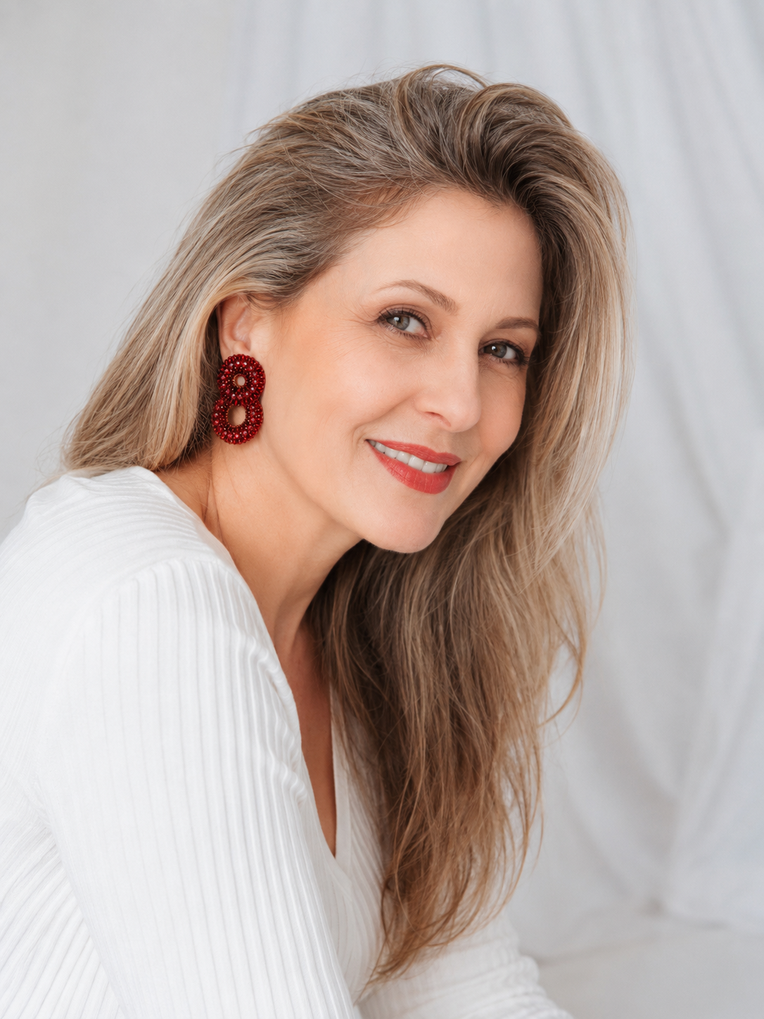 Woman wearing red earrings against a plain background. Red hand-crocheted double-circle cascade earrings with sparkling crystals and glass beads, handmade in Brazil with enameled copper wire.