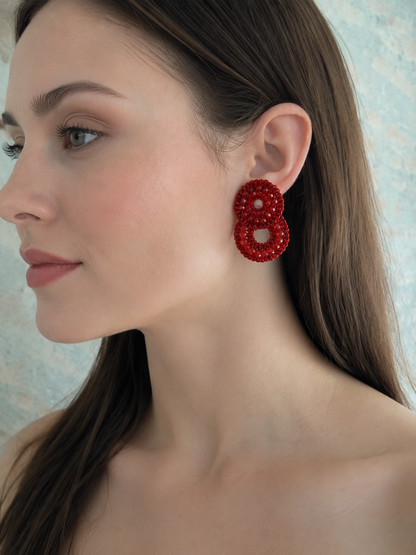 Woman wearing red beaded earrings with a neutral background. Red Velvet Hand-Crocheted Crystal Cascade Earrings. Handmade Brazilian Jewelry