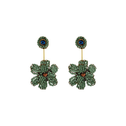 A pair of handmade beaded flower drop earrings featuring textured green petals, a central copper-brown bead, and a blue stone set in a gold-tone circular stud. Shop Riviera Mix Blossom Drop Earrings, handcrafted in Brazil with 18K gold filled and enameled wire. Lightweight floral statement earrings with colorful details.