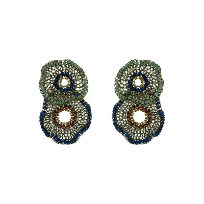 A pair of large, circular beaded earrings with a layered design. The earrings feature textured green, deep blue, and brown beaded rings with openwork centers, set against a plain white background. Shop Riviera Mix Crista Duo Earrings, handcrafted in Brazil with 18K gold filled and enameled wire. Lightweight statement earrings with colorful bead accents.