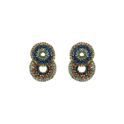 A pair of handmade beaded earrings with a double-stacked circular design. The earrings feature concentric rings of metallic gold, light green, dark blue, and copper-brown seed beads, with a central open space. Shop Riviera Mix Gush Small Earrings, hand-crocheted in Brazil with 18K gold-filled wire and sparkling blue, sage and bronze crystals.