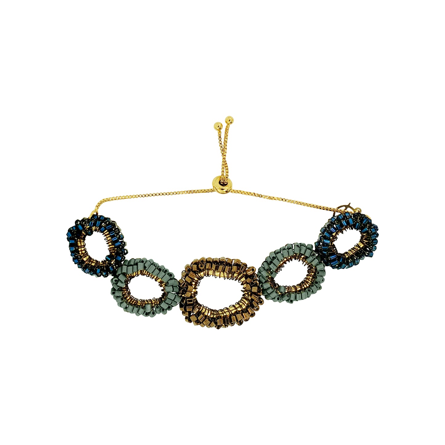 A beaded stretch bracelet featuring five interlocking oval links in shades of green, gold, and dark blue, suspended from a thin gold chain with an adjustable toggle clasp, shown on a plain white background. Shop the Riviera Mix Halo Bracelet, handcrafted in Brazil with colorful crochet links, enameled wire and an elegant adjustable design.