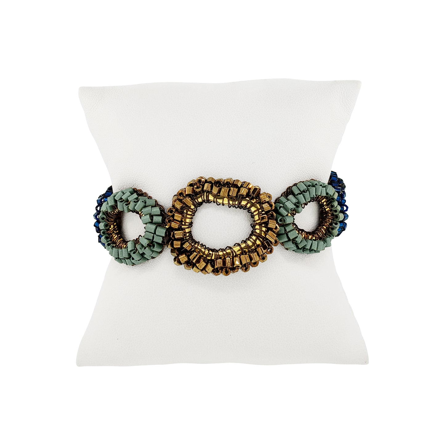 A beaded stretch bracelet with three oval links, featuring a central gold-toned link flanked by sage green and dark blue beaded oval links, displayed on a white mannequin stand.