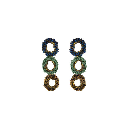 A pair of beaded drop earrings with three stacked circular rings in navy blue, sage green, and gold-tone metal on a plain white background. Shop Riviera Mix Halo Earrings, handcrafted in Brazil with 18K gold filled wire and shimmering crystals. Lightweight, colorful statement earrings.