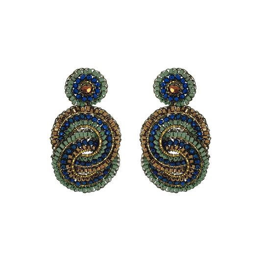 A pair of handmade beaded drop earrings featuring a spiral design in green, blue, and gold, with a small round green and blue top piece on each earring, set against a plain white background. Shop Riviera Mix Loki Earrings, handcrafted in Brazil with 18K gold filled and enameled wire, colorful crystals and intricate crochet detailing.