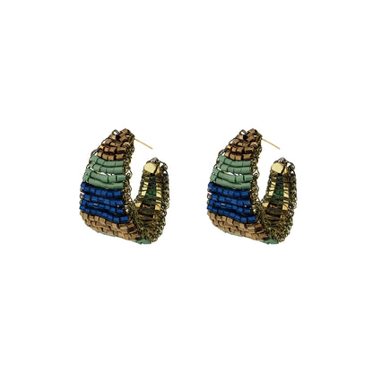 A pair of handmade beaded hoop earrings with a layered design of brown, green, and blue seed beads, shown on a plain white background. Shop Riviera Mix Nyx Hoop Earrings, hand-crocheted in Brazil with enameled wire in blue, sage green and bronze for a lightweight statement look.
