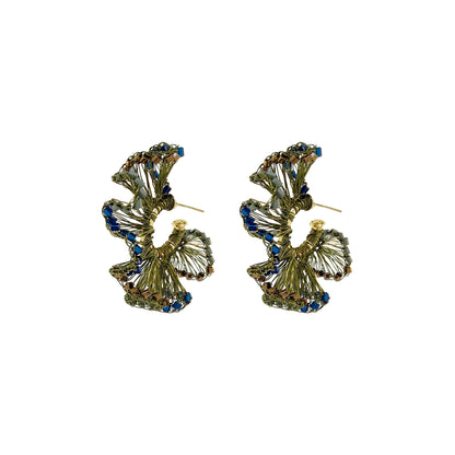 A pair of gold-toned statement earrings with a layered, textured design accented by small blue rhinestones, shown on a plain white background. Riviera Mix Rio Hoop handmade crochet earrings with ruffled deep blue, sage green and bronze accents in 18 karat gold filled and enameled wire.