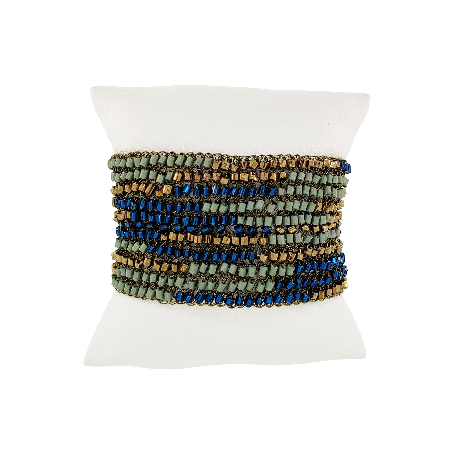 Multicolored beaded bracelet on a white mannequin wrist against a white background. Riviera Mix Signature handmade crochet cuff bracelet with woven deep blue, sage green and bronze accents and gold-tone magnetic clasp.