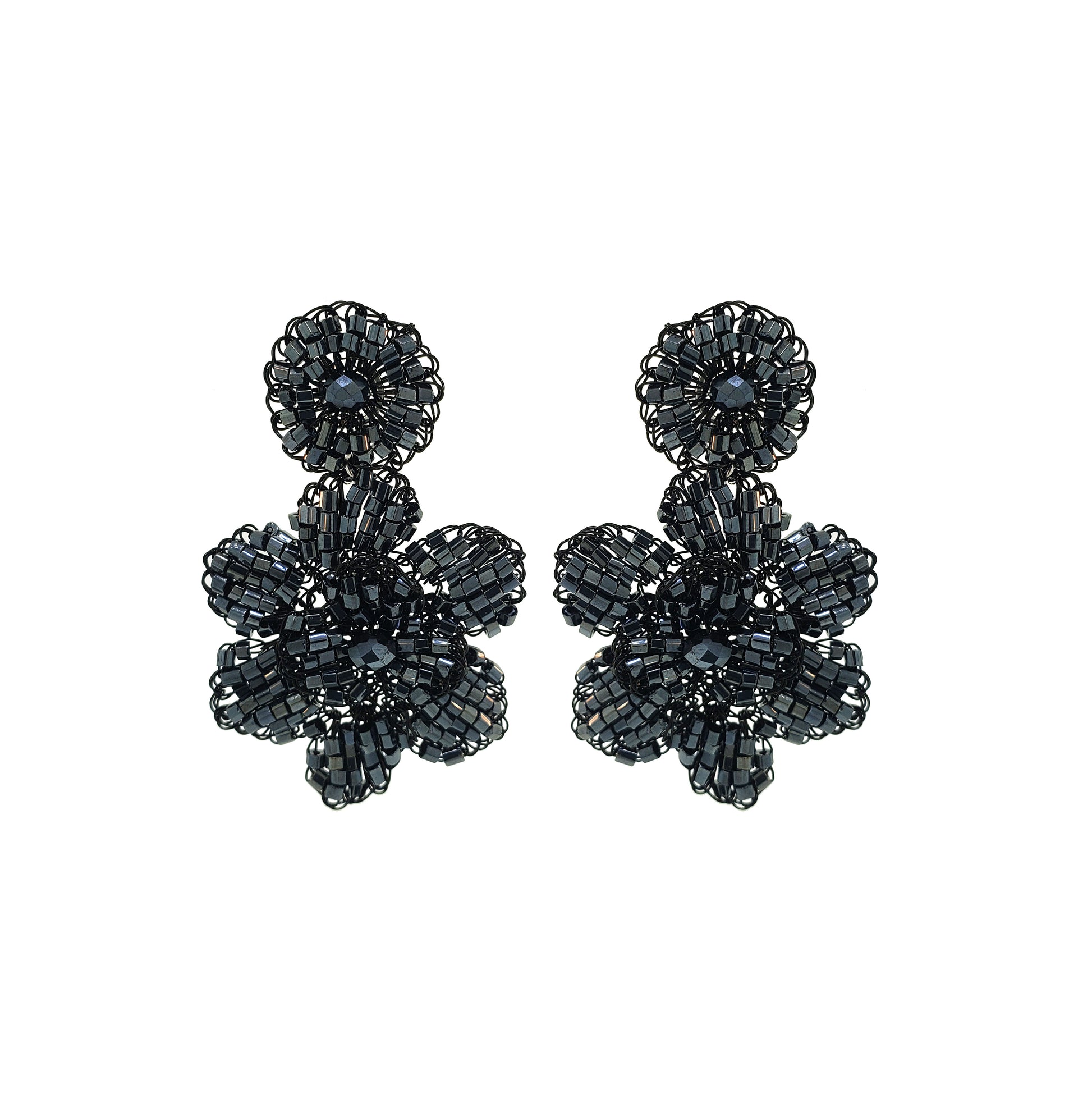 A pair of hand-crocheted floral earrings made with black enameled copper wire, displayed against a white background. Mini floral hand-crocheted dangle earrings handmade in Brazil with shiny black enameled wire and deep charcoal bead accents.