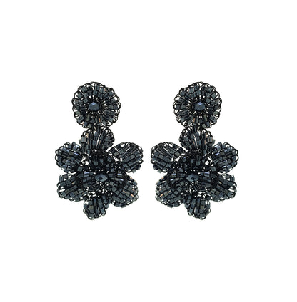 A pair of hand-crocheted floral earrings made with black enameled copper wire, displayed against a white background. Mini floral hand-crocheted dangle earrings handmade in Brazil with shiny black enameled wire and deep charcoal bead accents.