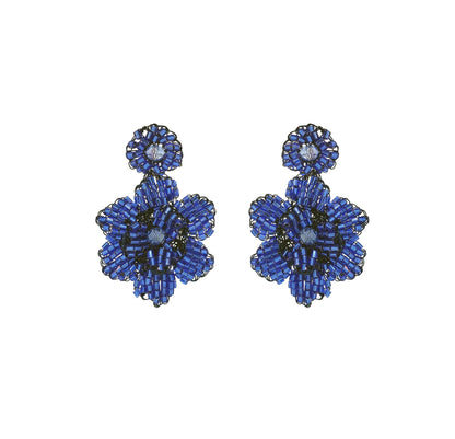 A pair of hand-crocheted floral earrings in blue, made from enameled wire, with hypoallergenic properties. Mini floral hand-crocheted earrings handmade in Brazil with enameled wire, lightweight artisan design, and delicate floral texture.