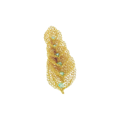 A gold-toned openwork mesh feather-shaped brooch with small light blue-green gemstone accents, shown on a plain white background. Discover the Seafoam Blue Calla Embrace Maxi Brooch. Hand-crocheted in Brazil with 18K gold-filled wire and sparkling seafoam crystals. Elegant wearable art.