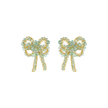 A pair of gold bow-shaped stud earrings embellished with light green faceted rhinestones, shown against a plain white background. Seafoam Bow Blossom Drop handmade crochet earrings featuring delicate bow-shaped designs with sparkling seafoam blue crystals, gold-filled wire, and dangling crystal details.