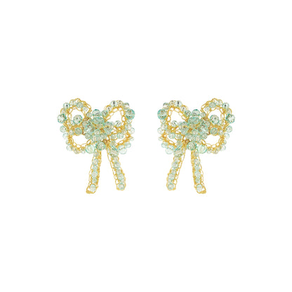 A pair of gold bow-shaped stud earrings embellished with light green faceted rhinestones, shown on a plain white background. Shop Seafoam Bow Blossom Drop Earrings. Handmade in Brazil with seafoam blue crystals and 18K gold-filled wire. Lightweight, feminine, and elegant.