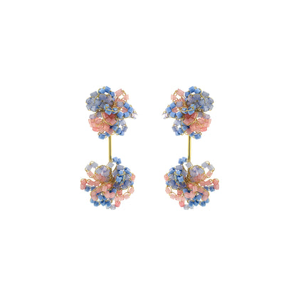 Pair of floral earrings with pink and blue stones on a white background. Drizzle hand-crocheted dangle earrings made with 18 karat gold filled wire, handcrafted in Brazil with hypoallergenic and nickel-free materials.