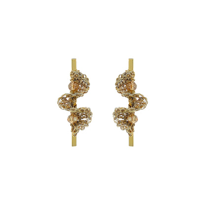 A pair of gold-toned statement earrings with intricate, textured spiral wirework and small clear bead accents, displayed on a solid white background. Hand-crocheted gold bar drop earrings with sculptural ruffled wirework and champagne crystal accents, handmade in Brazil.