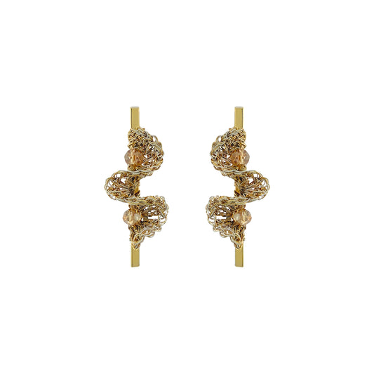 A pair of gold-toned statement earrings with intricate, textured spiral wirework and small clear bead accents, displayed on a solid white background. Hand-crocheted gold bar drop earrings with sculptural ruffled wirework and champagne crystal accents, handmade in Brazil.