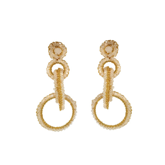 A pair of hand-crocheted earrings made with 18 karat gold filled wire, featuring a loop design with sparkling crystals and beads, on a white background. Interlocked link hand-crocheted earrings handmade in Brazil with 18 karat gold filled wire, soft champagne-toned beads, sparkling crystal accents, and layered circular links.