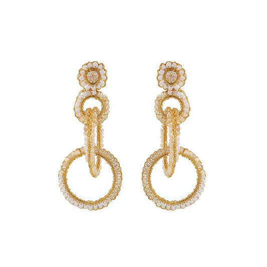A pair of gold-filled, hand-crocheted earrings with sparkling crystals, featuring interlocked links and floral details. Interlocked link hand-crocheted earrings handmade in Brazil with 18 karat gold filled wire, soft ivory beads, sparkling crystal accents, and layered circular links.